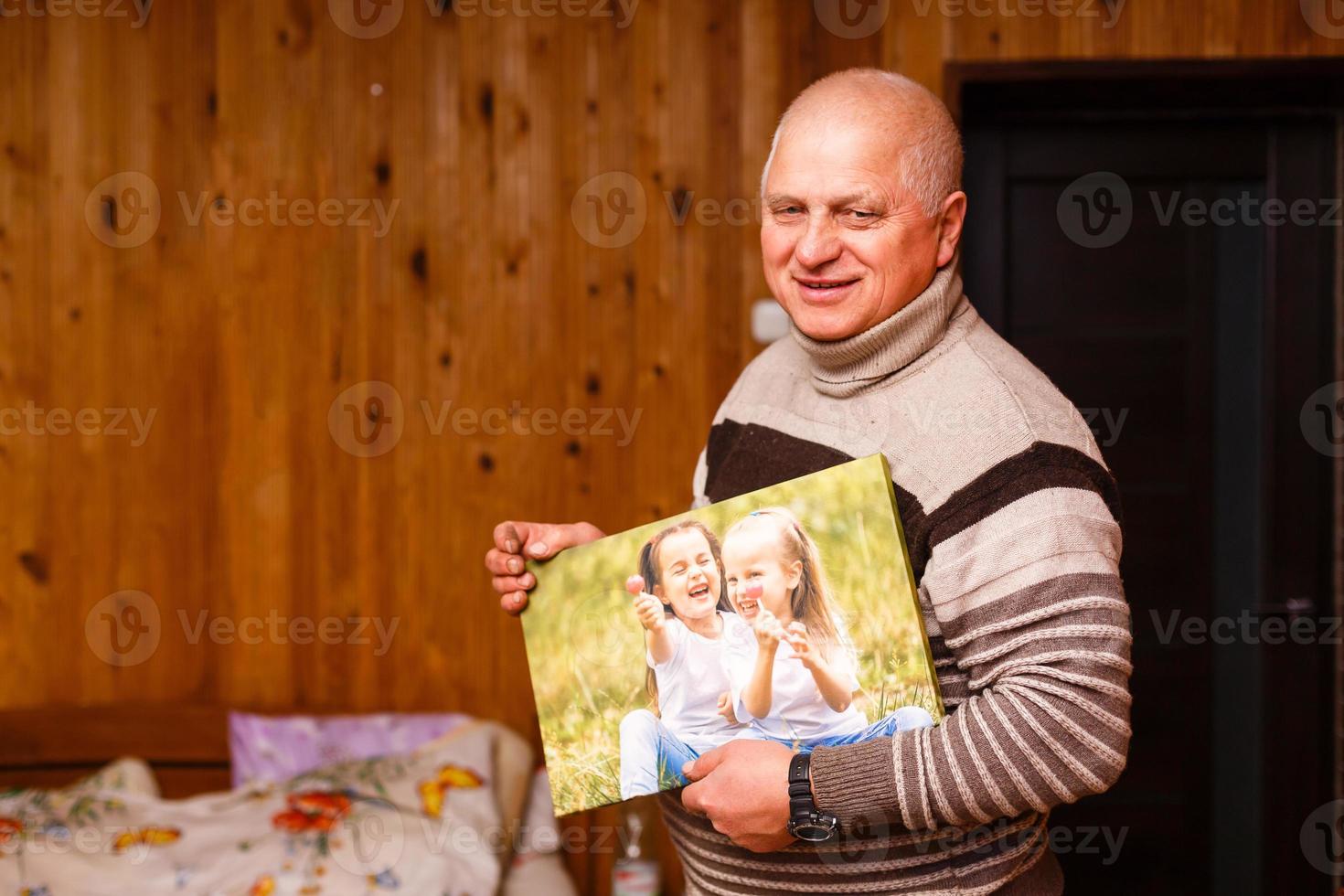 ouderen Mens Holding een foto canvas in een houten huis
