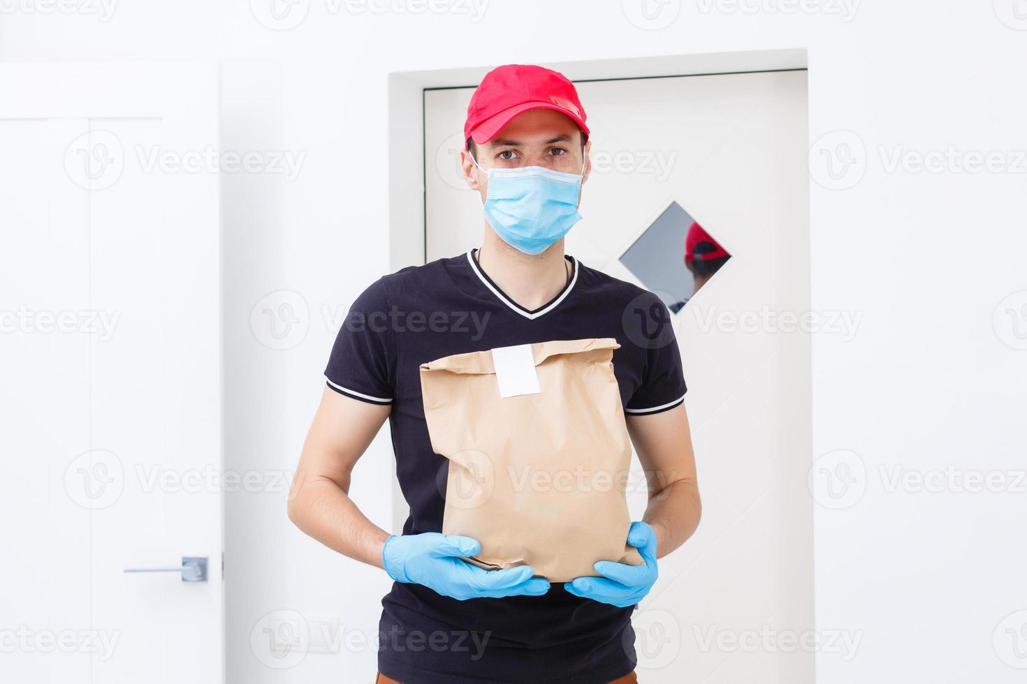 levering Mens Holding papier zak met voedsel Aan wit achtergrond, voedsel levering Mens in beschermend masker en beschermend handschoenen foto