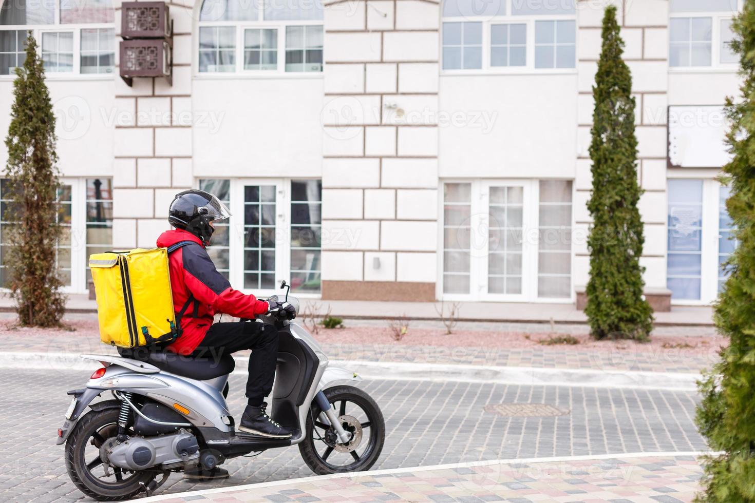 geel levering doos Aan motorfiets met levering Mens in voorkant van huis. foto