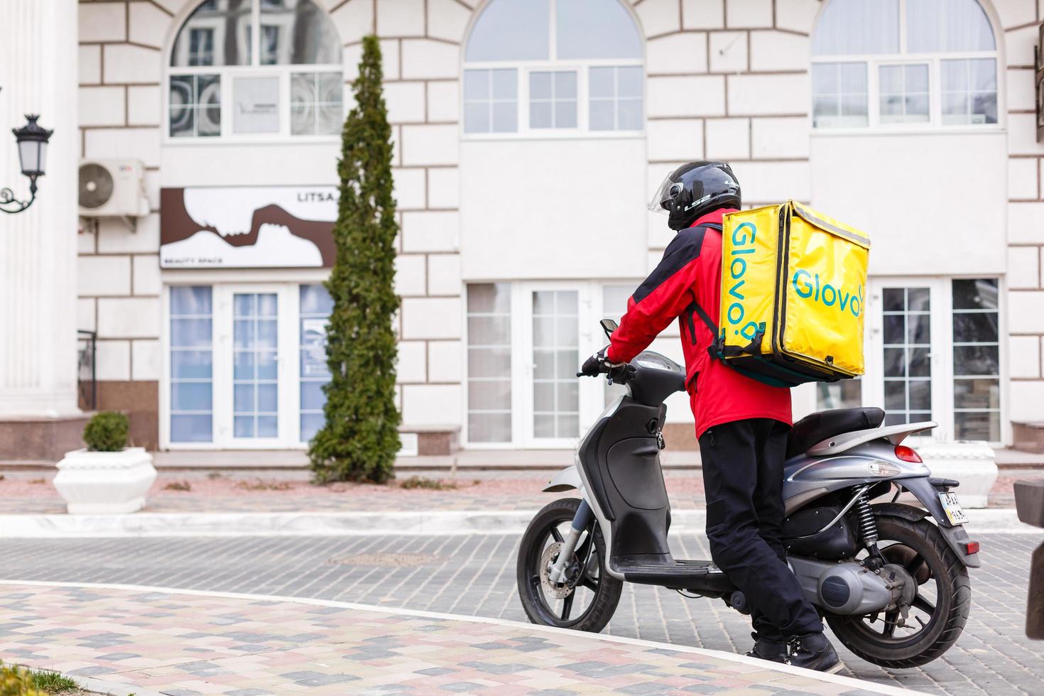 geel levering doos Aan motorfiets met levering Mens in voorkant van huis. foto