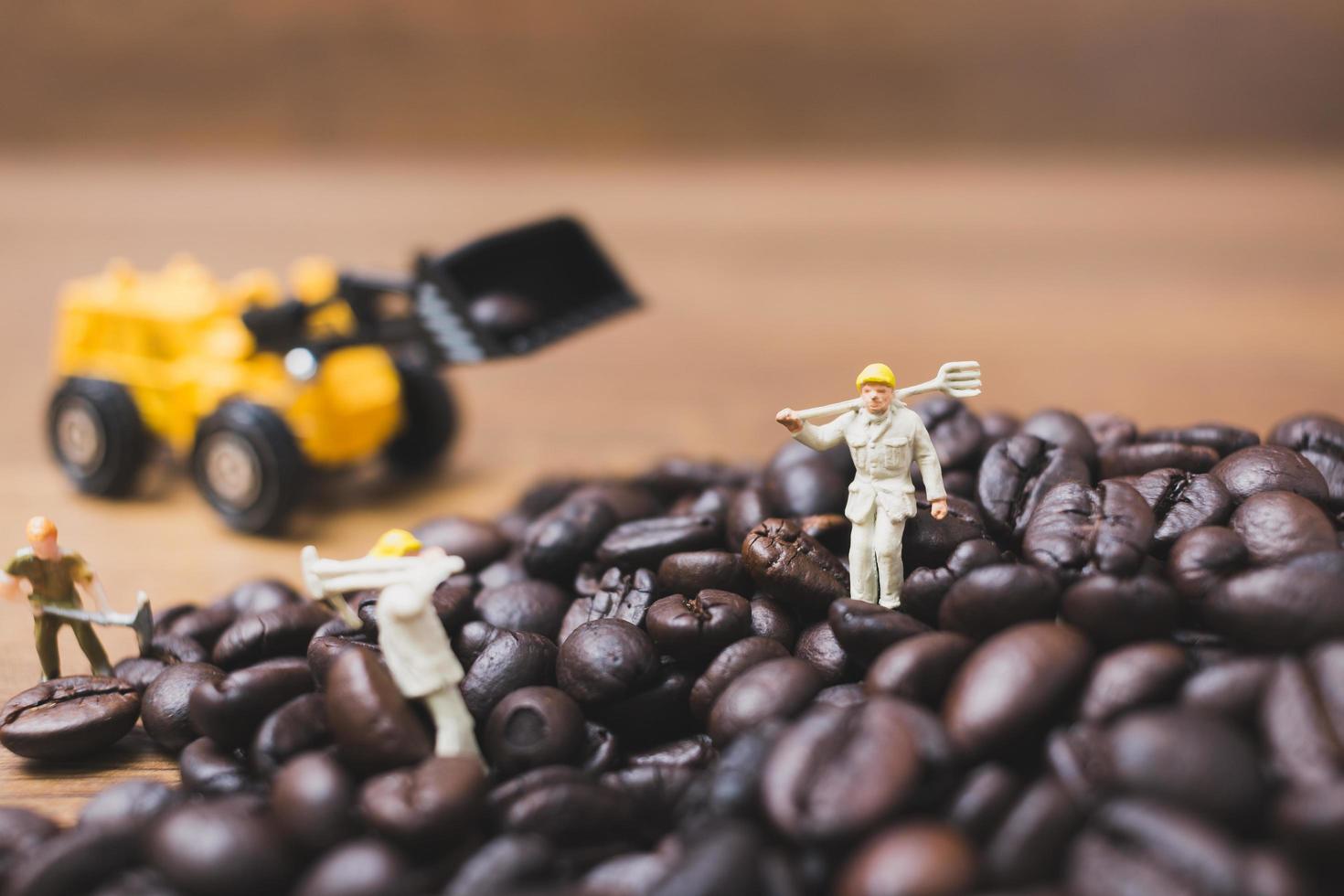 miniatuurmensen die aan gebrande koffiebonen werken foto