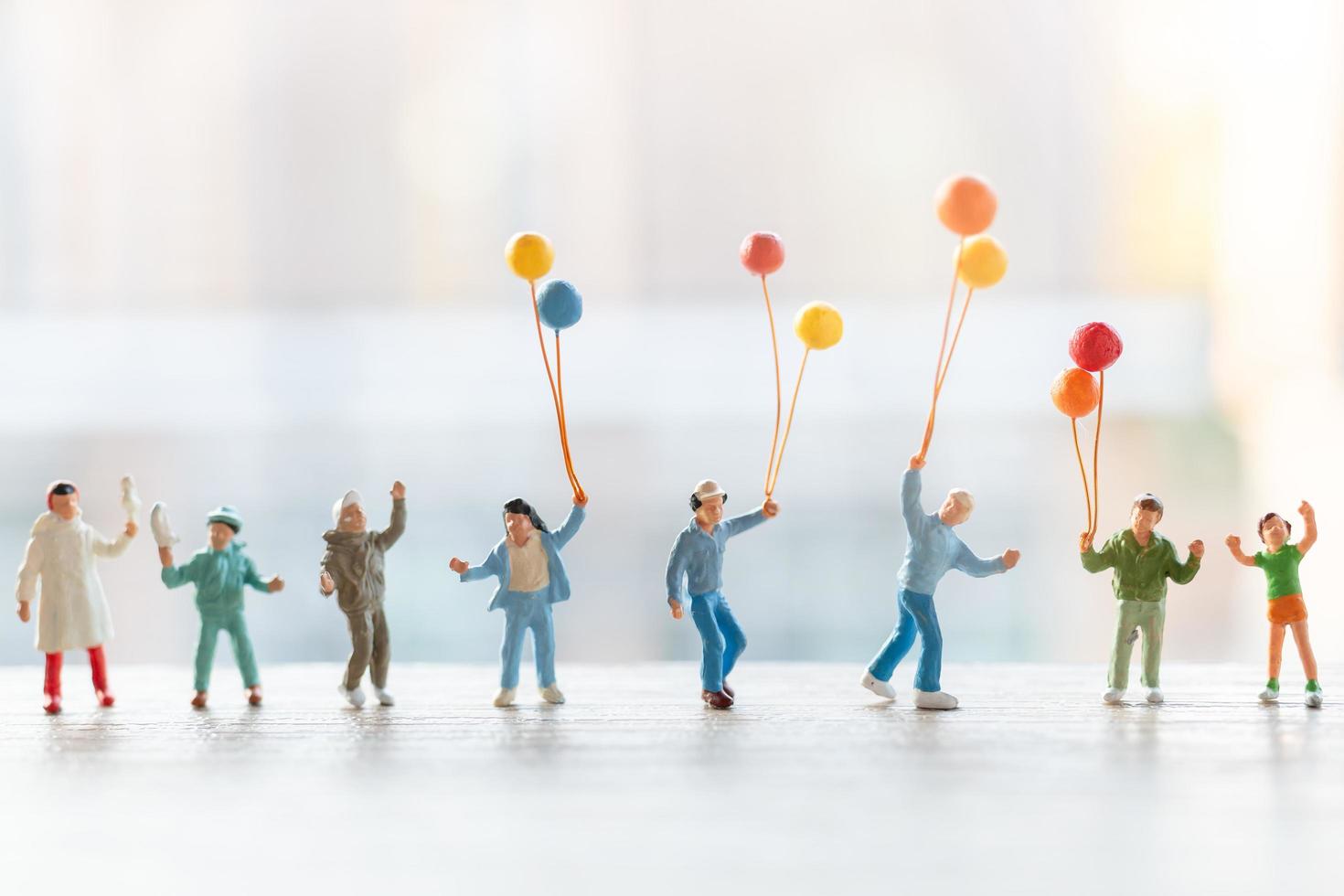 miniatuurmensen die met ballons lopen, gelukkig familieconcept foto