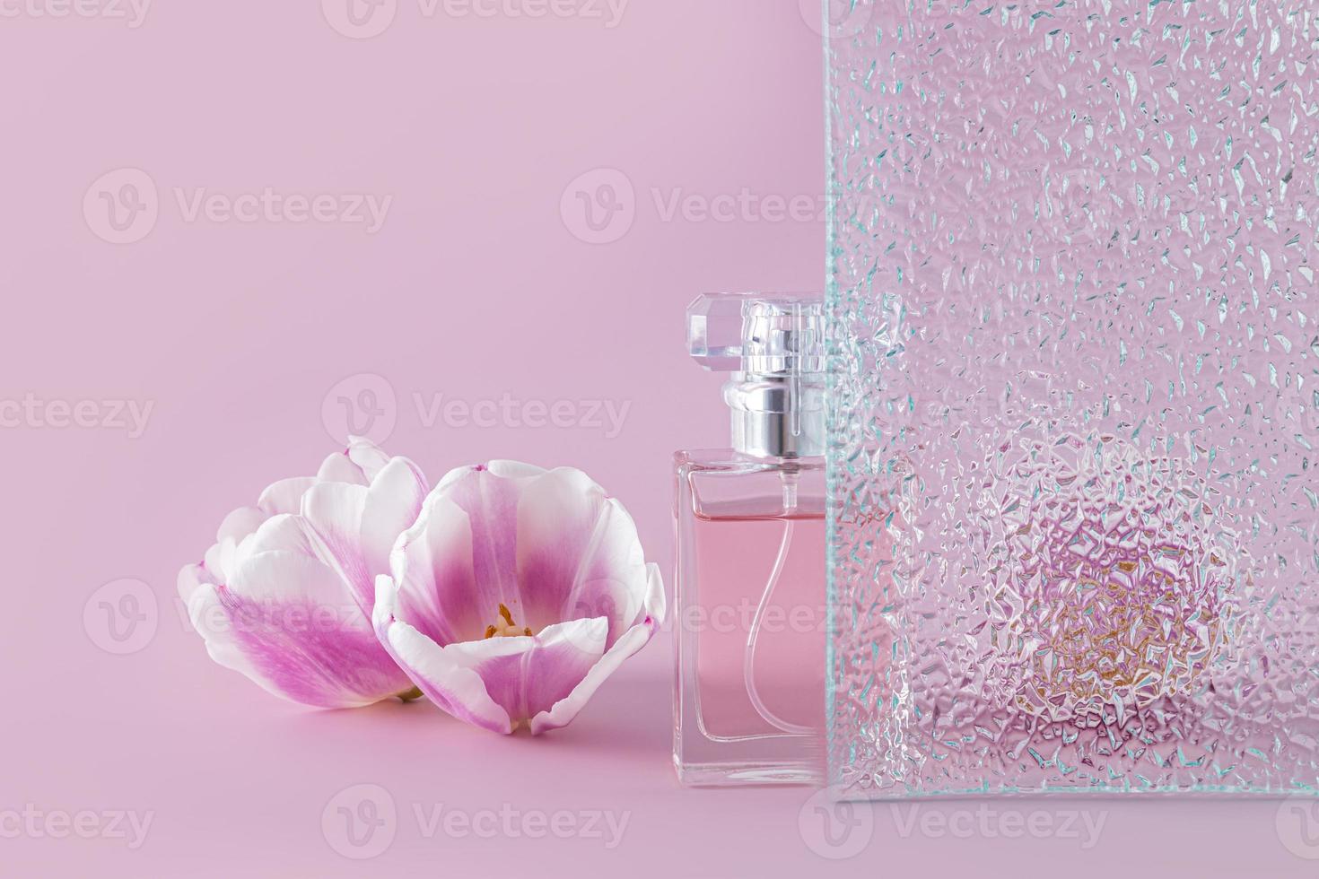 creatief samenstelling met een mooi fles van vrouwen parfum, reliëf glas en delicaat voorjaar bloemen. voorkant visie. lila achtergrond. foto