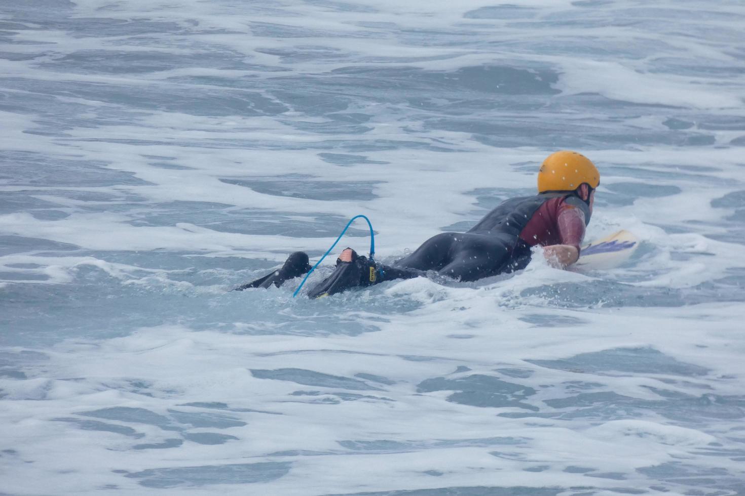 surfers krijgen klaar naar invoeren de water en wandelen met de bord langs de oever. foto