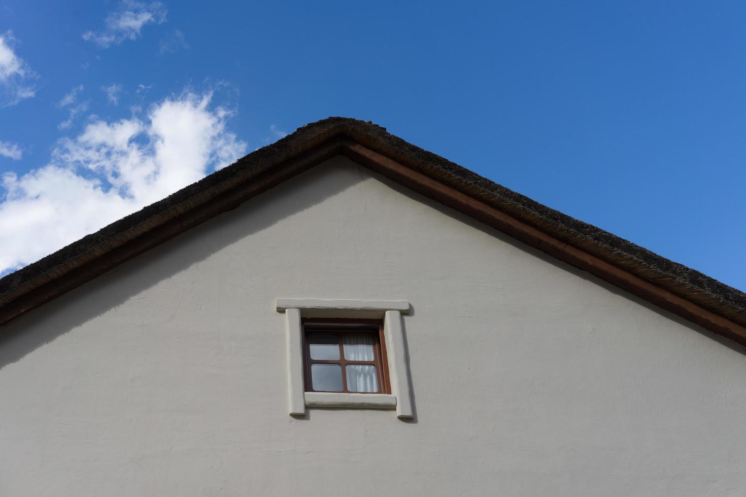 onderdeel van een rieten dak van een dorpshuis met een bewolkte blauwe hemel foto