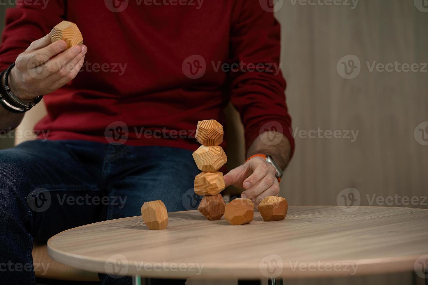 mannetje handen zetten samen verschillend figuren van houten veelvlakken, eco spellen voor volwassenen en kinderen, anti stress speelgoed gemaakt van natuurlijk hout foto