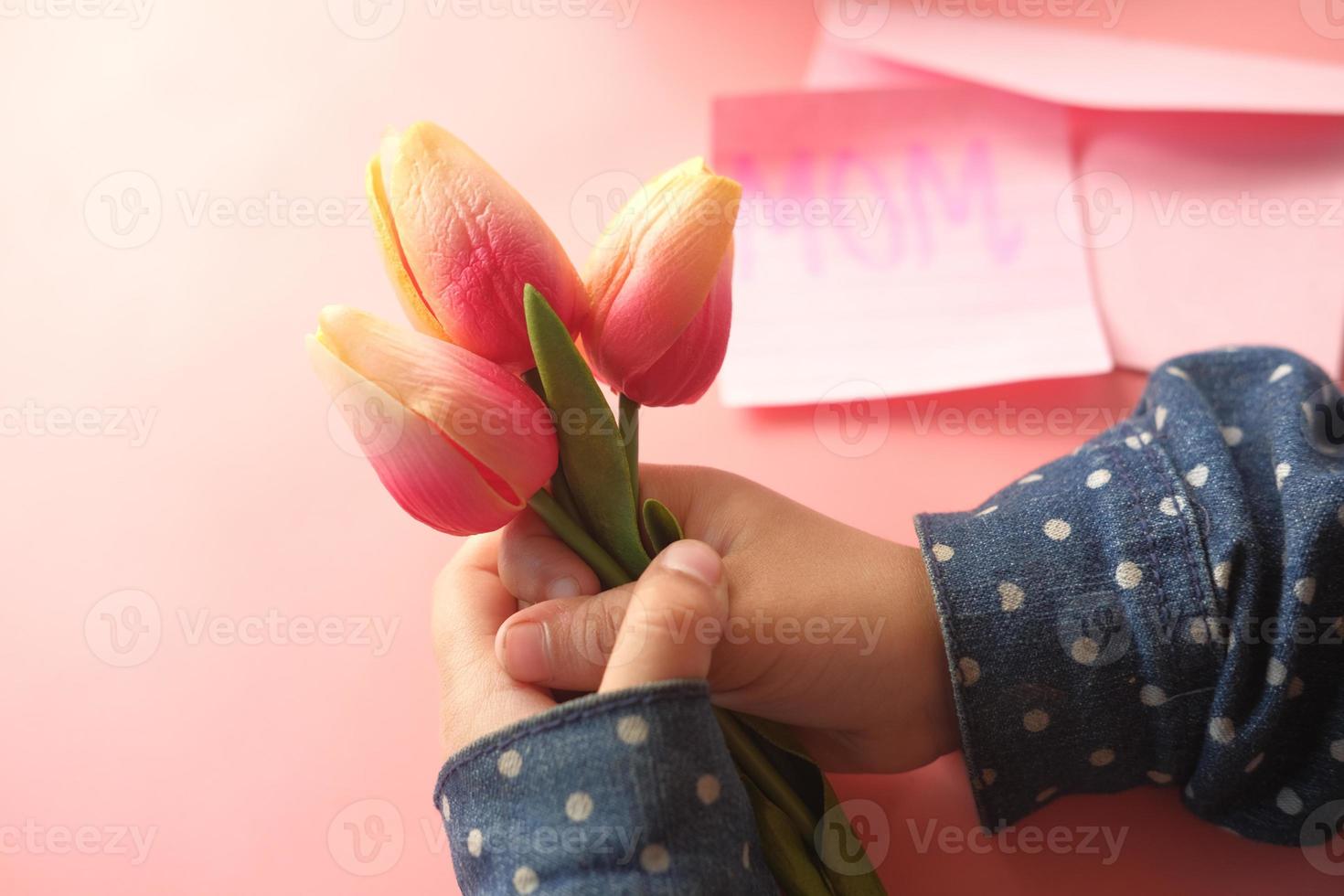 kind hand met tulp bloem foto