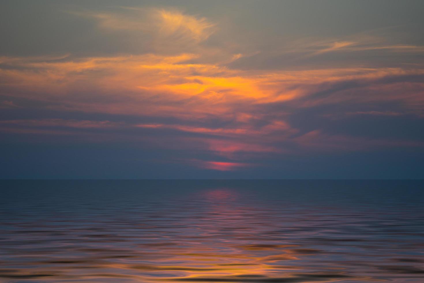 donkeroranje bewolkte zonsondergang over een watermassa foto