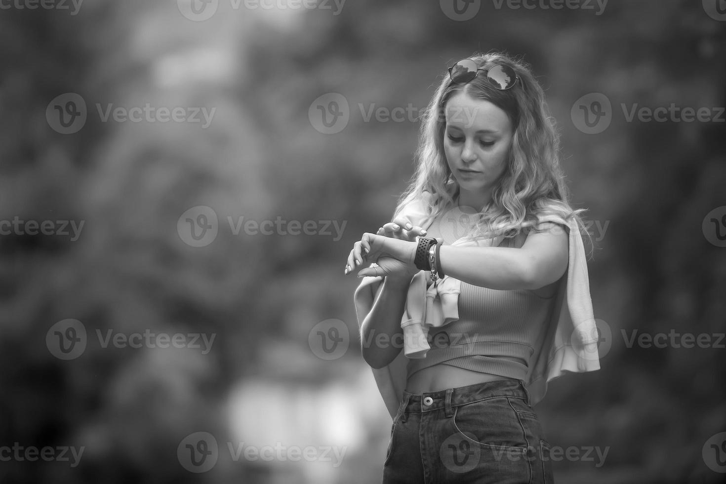 jong toerist vrouw met lang golvend haar- looks Bij haar slim kijk maar telefoon terwijl wandelen, kopiëren ruimte. zwart en wit foto. foto