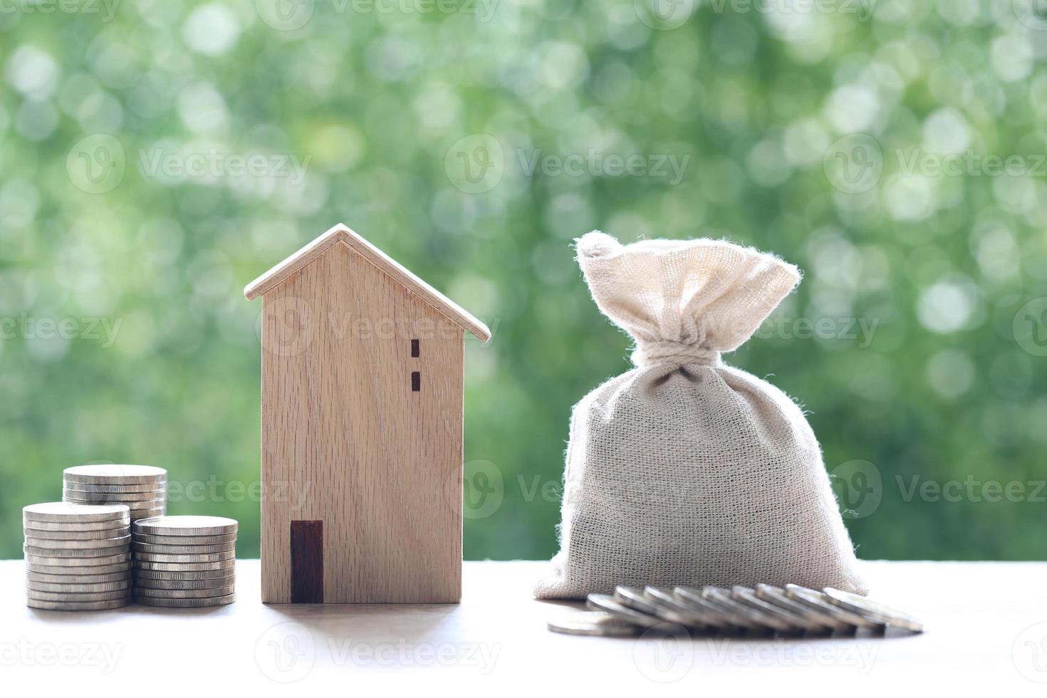 modelhuis met een stapel munten op een natuurlijke groene achtergrond, geld besparen ter voorbereiding op het toekomst- en investeringsconcept foto