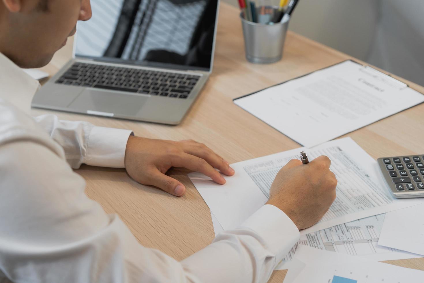 dichtbij omhoog hand- van spanning Aziatisch jong werknemer bedrijf Mens, mannetje berekenen belasting inkomen en uitgaven, rekeningen, credit kaart voor betaling of betaaldag Aan tafel Bij huis kantoor. financieel, financiën mensen concept. foto