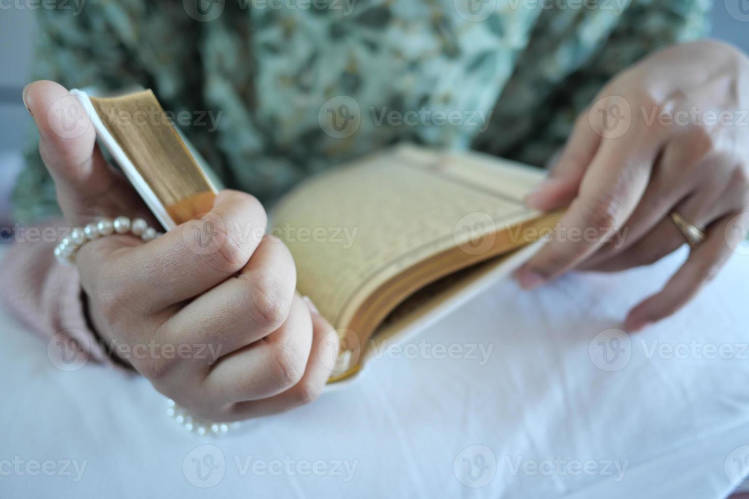 de hand van moslimvrouwen die 's nachts de koran lezen foto