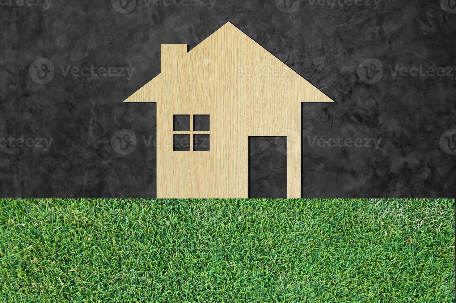 huis icoon van houten Aan gras structuur natuur achtergrond net zo symbool van hypotheek, droom huis Aan natuur achtergrond en ruimte voor uw tekst foto
