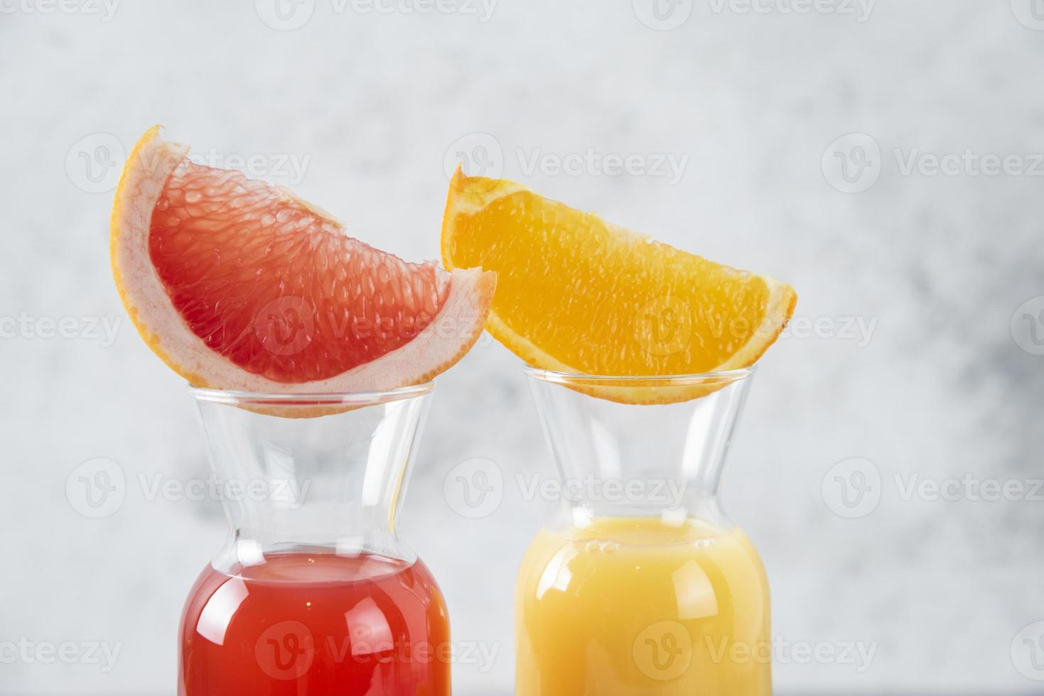 twee glazen grapefruit en sinaasappelsap op een stenen achtergrond foto