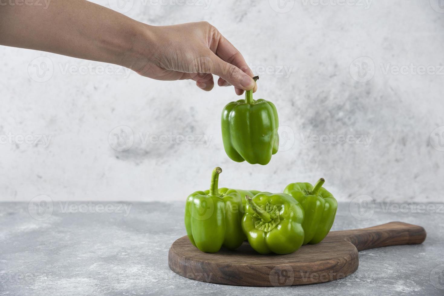 mannelijke hand met een groene paprika op een stenen achtergrond foto