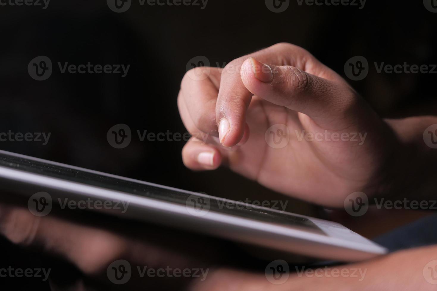 iemands hand met behulp van digitale tablet op zwarte achtergrond foto