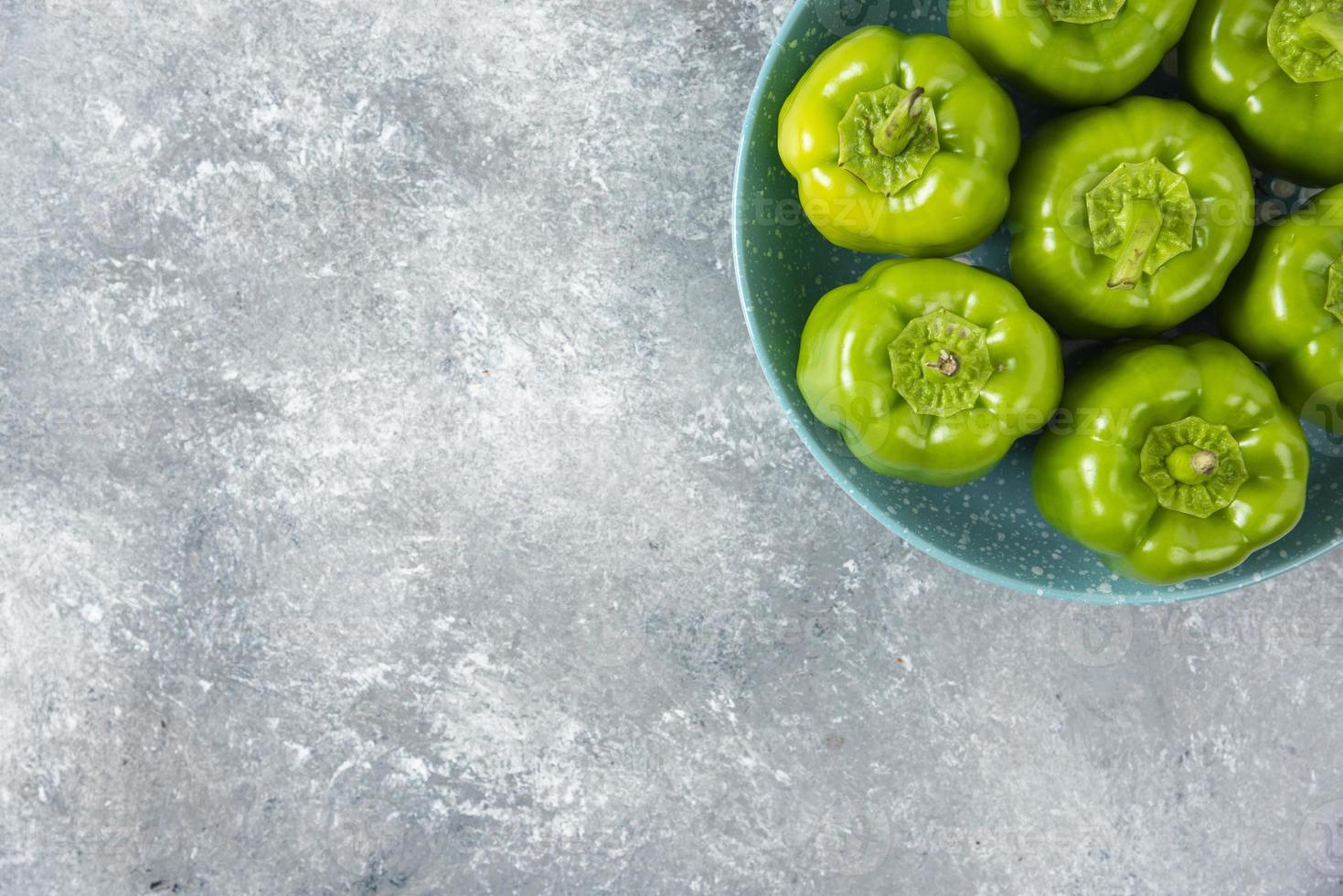 verse groene paprika geplaatst op een blauw bord op een stenen tafel foto