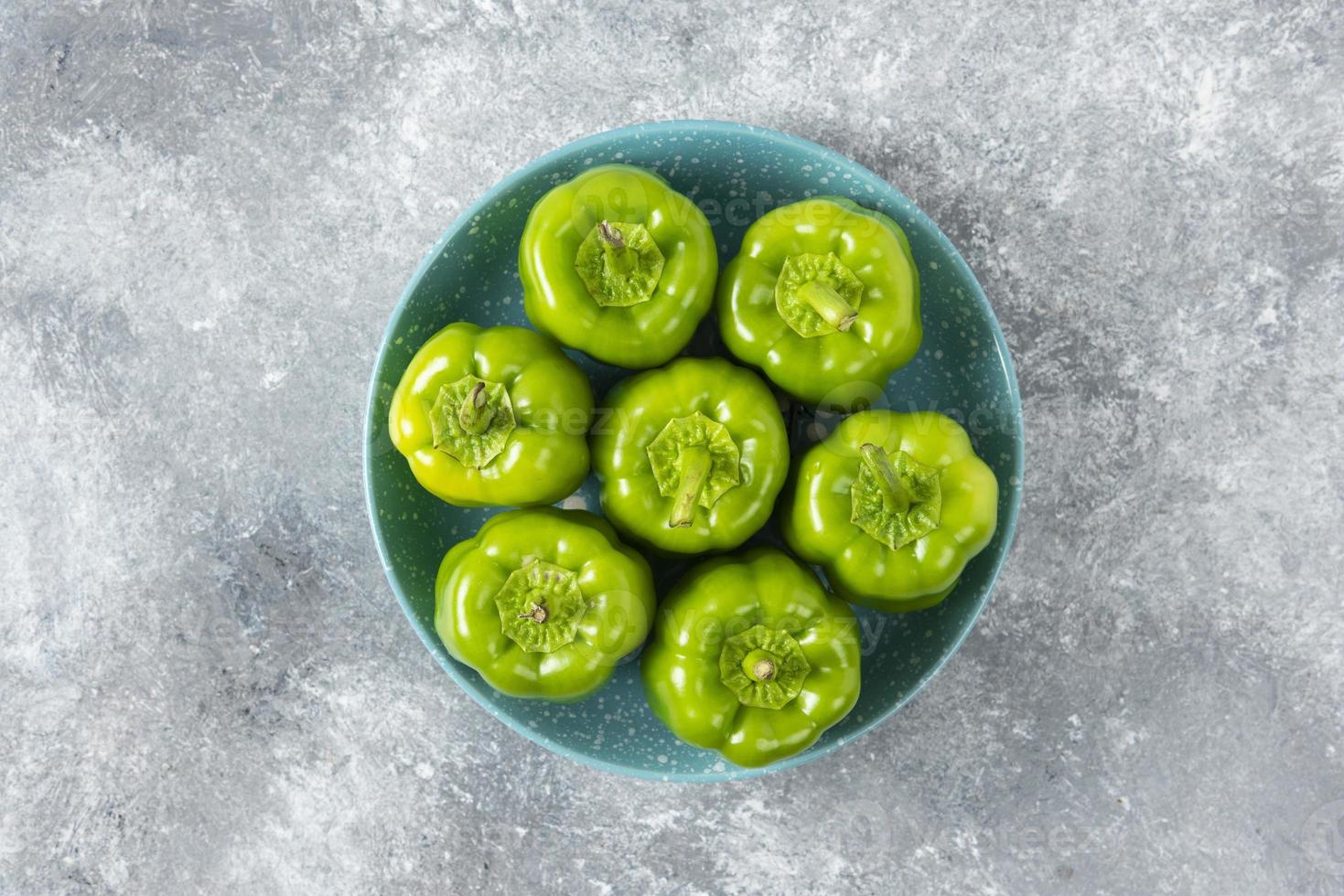 verse groene paprika geplaatst op een blauw bord op een stenen tafel foto