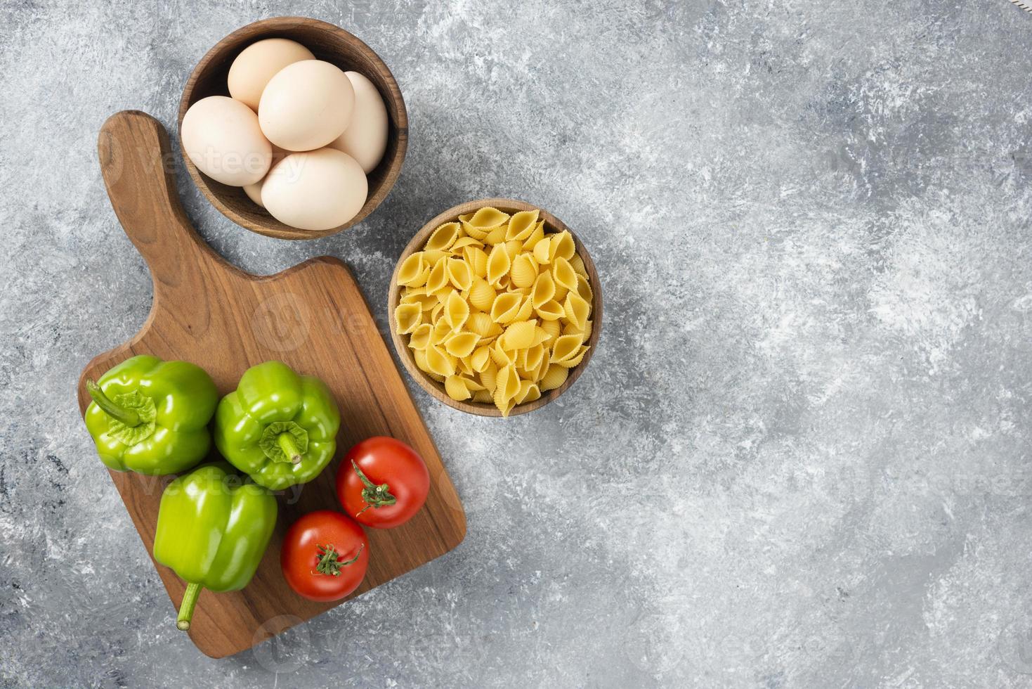 rauwe kippeneieren met ongekookte schelpvormige pasta en verse groenten foto