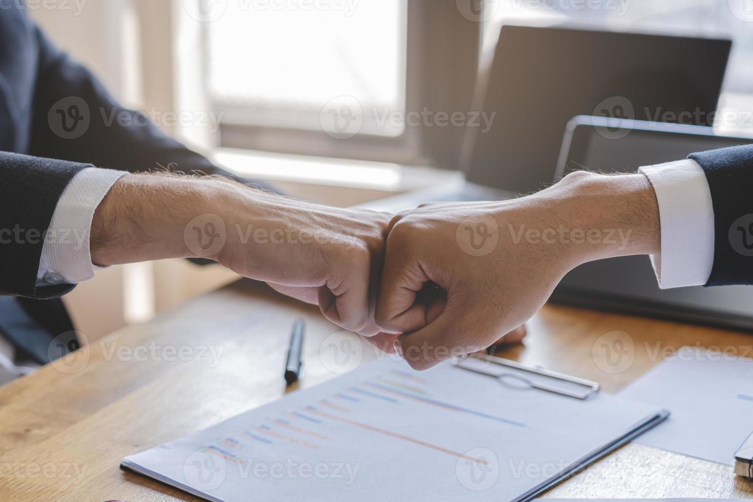 Proficiat, bedrijf vennootschap mensen, twee Aziatisch en Kaukasisch jong Mens vuist stoten, beven handen samen met vennootschap, klant of collega na werk is gedaan, succesvol. arbeider ontmoeting. foto