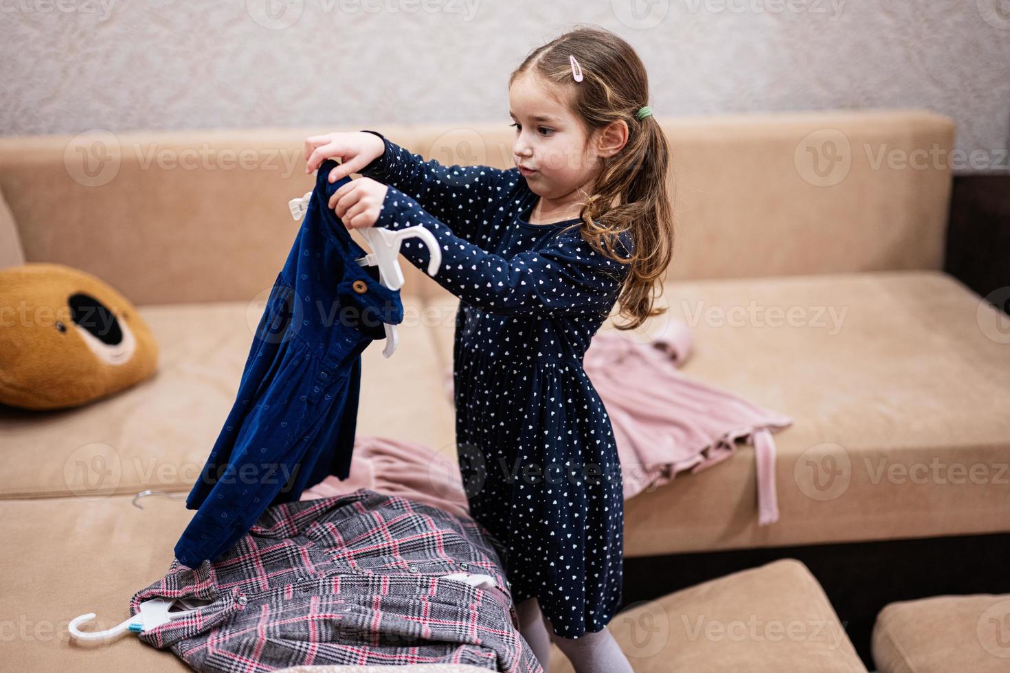 baby meisje kiezen kleren van de garderobe Bij huis Aan de bank. foto