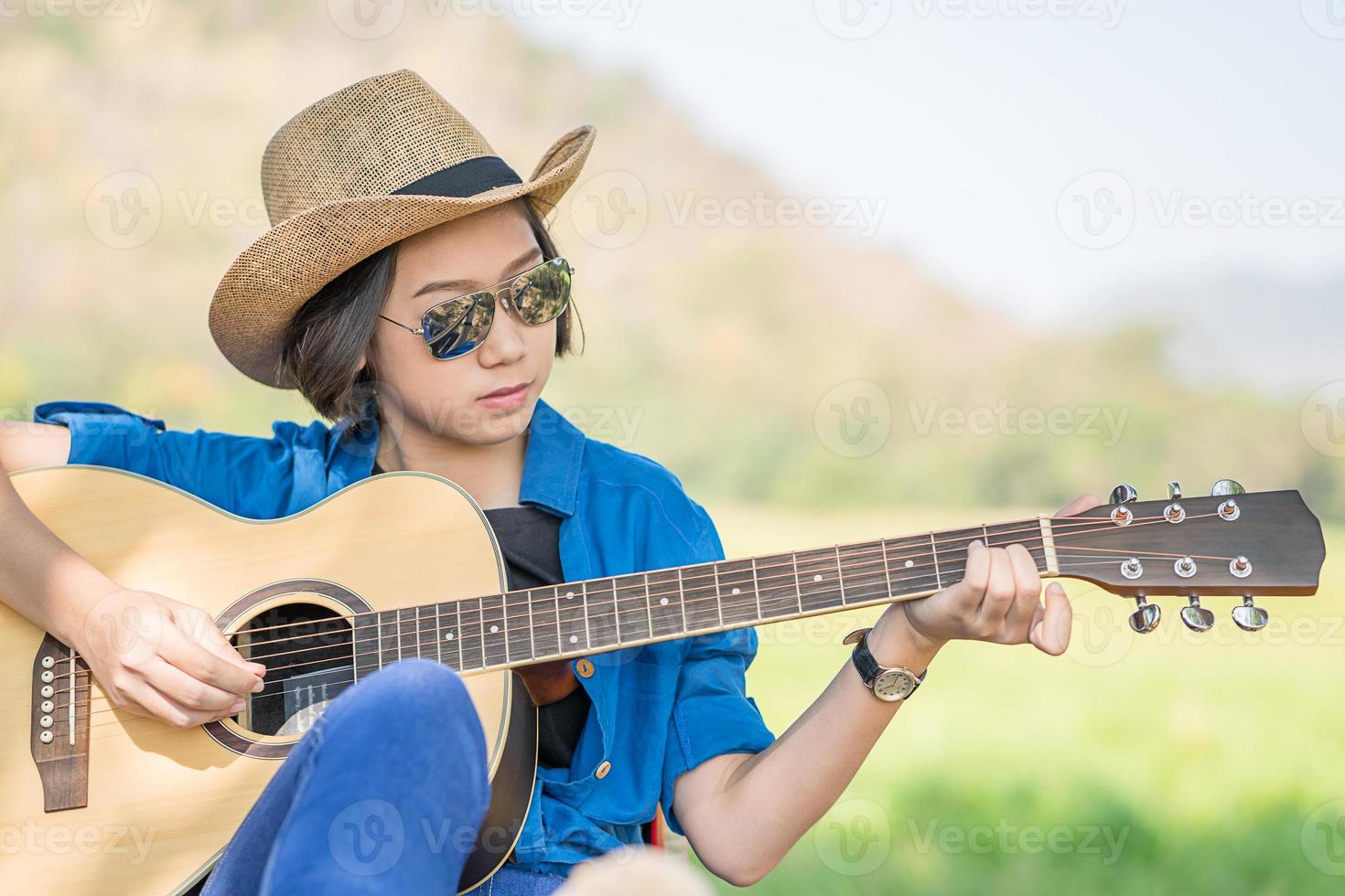 dichtbij omhoog vrouw slijtage hoed en spelen gitaar foto