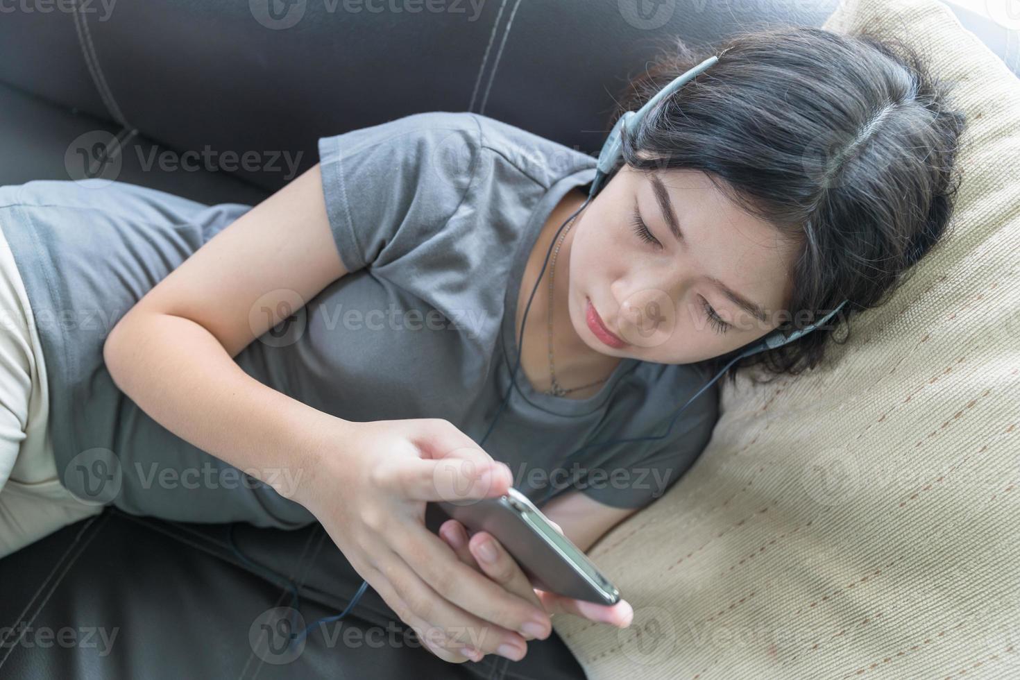 Aziatisch vrouw luisteren muziek- van mobiel telefoon foto