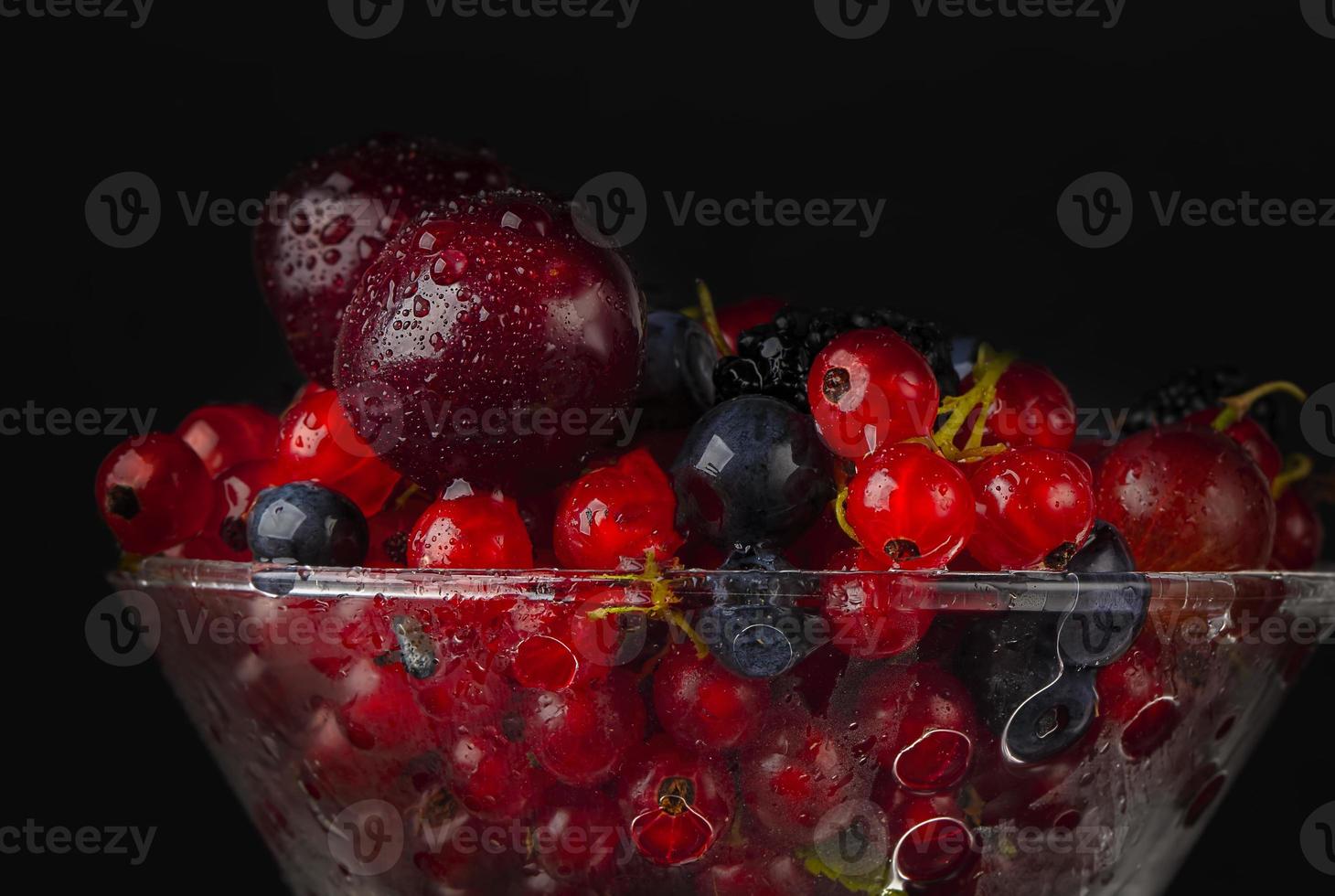 mooi rood bessen gegoten met water Aan een donker achtergrond detailopname. foto