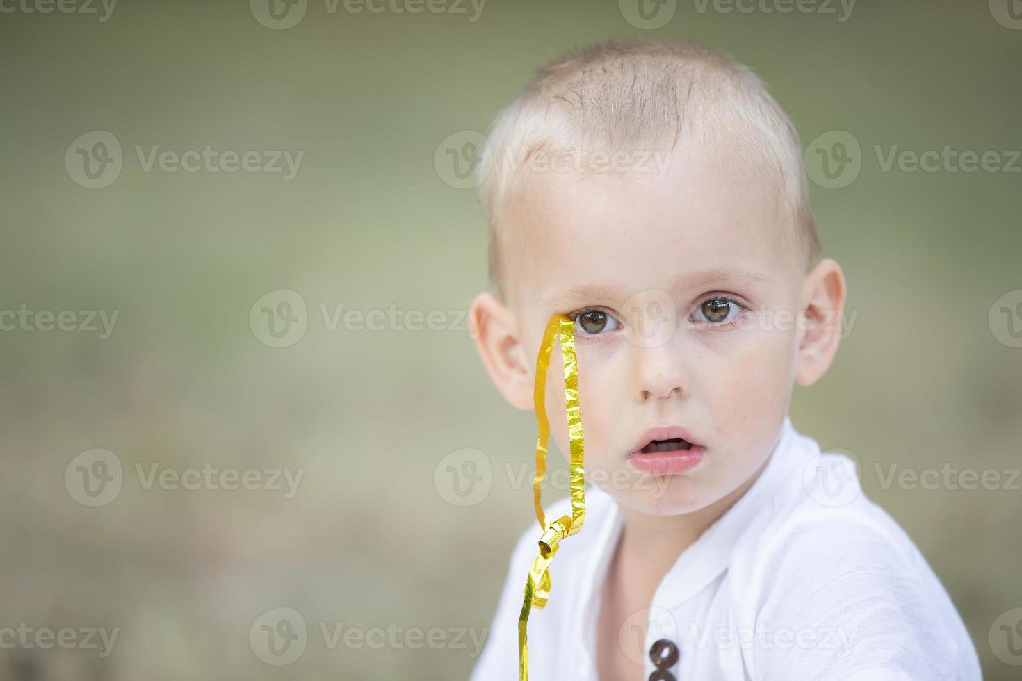 de gezicht van een weinig verrast jongen met een confetti lintje. foto