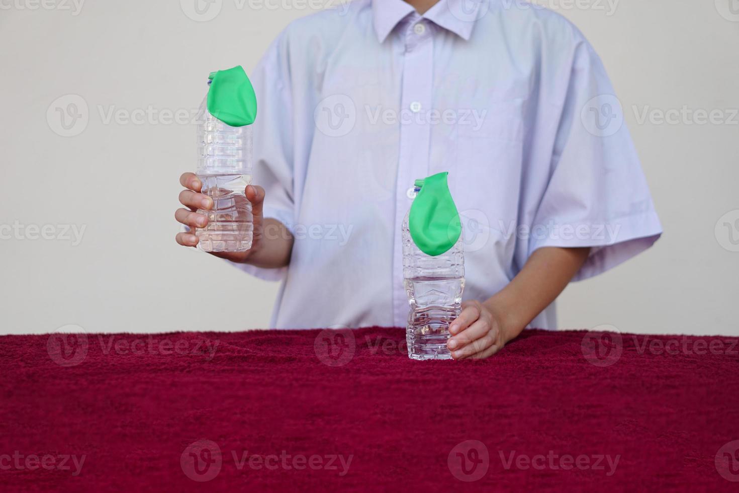 leerling studie wetenschap experiment, houden twee flessen met groen ballonnen Aan de top van flessen. concept, wetenschap experiment over reactie van chemisch substantie, azijn en bakken Frisdrank. eerste stap. foto