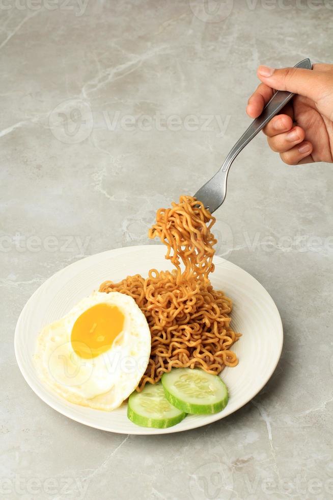 eten gebakken noodle indomie goreng, nemen noedels met vork foto