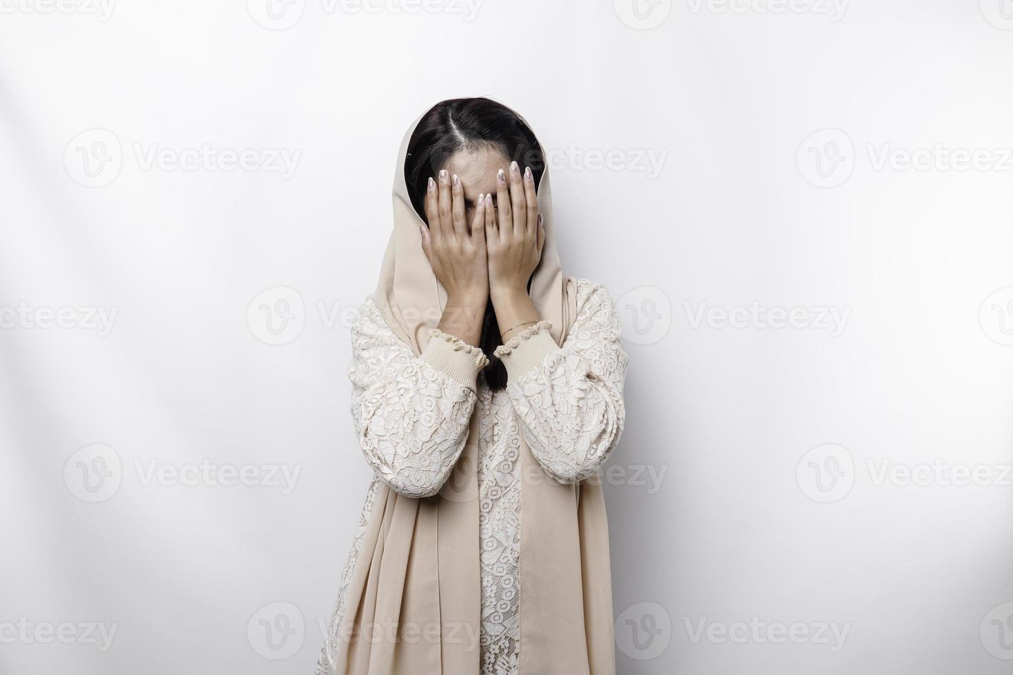 jong Aziatisch moslim vrouw geïsoleerd Aan wit achtergrond, looks depressief, gezicht gedekt door armen bang en zenuwachtig. foto
