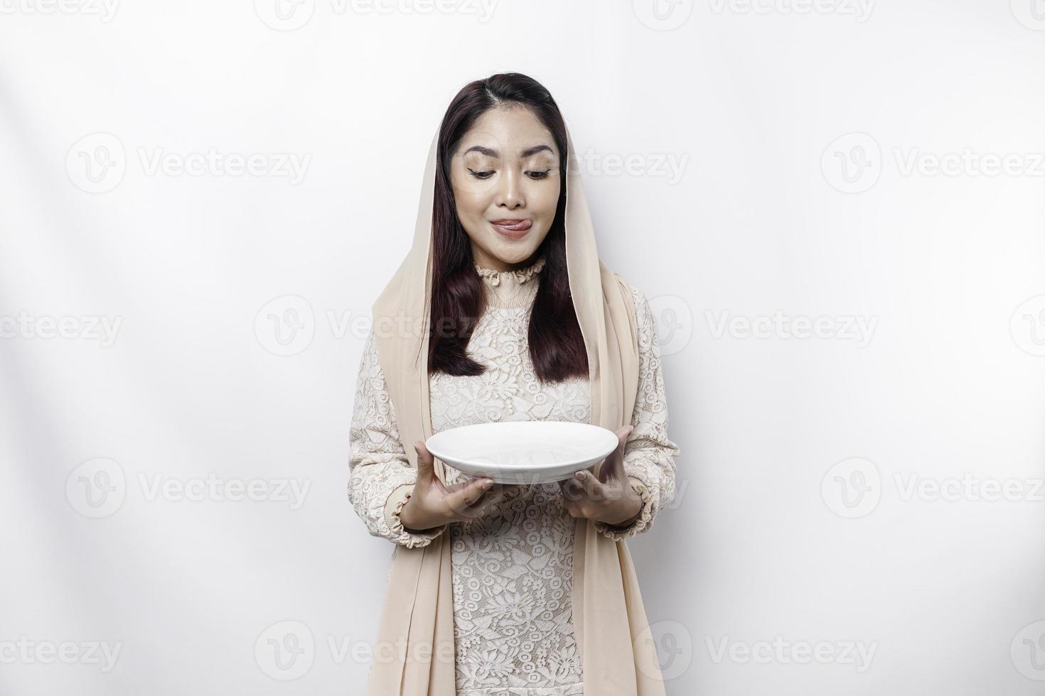 een Aziatisch moslim vrouw is vastend en hongerig en Holding gereedschap bestek terwijl op zoek terzijde denken over wat naar eten foto