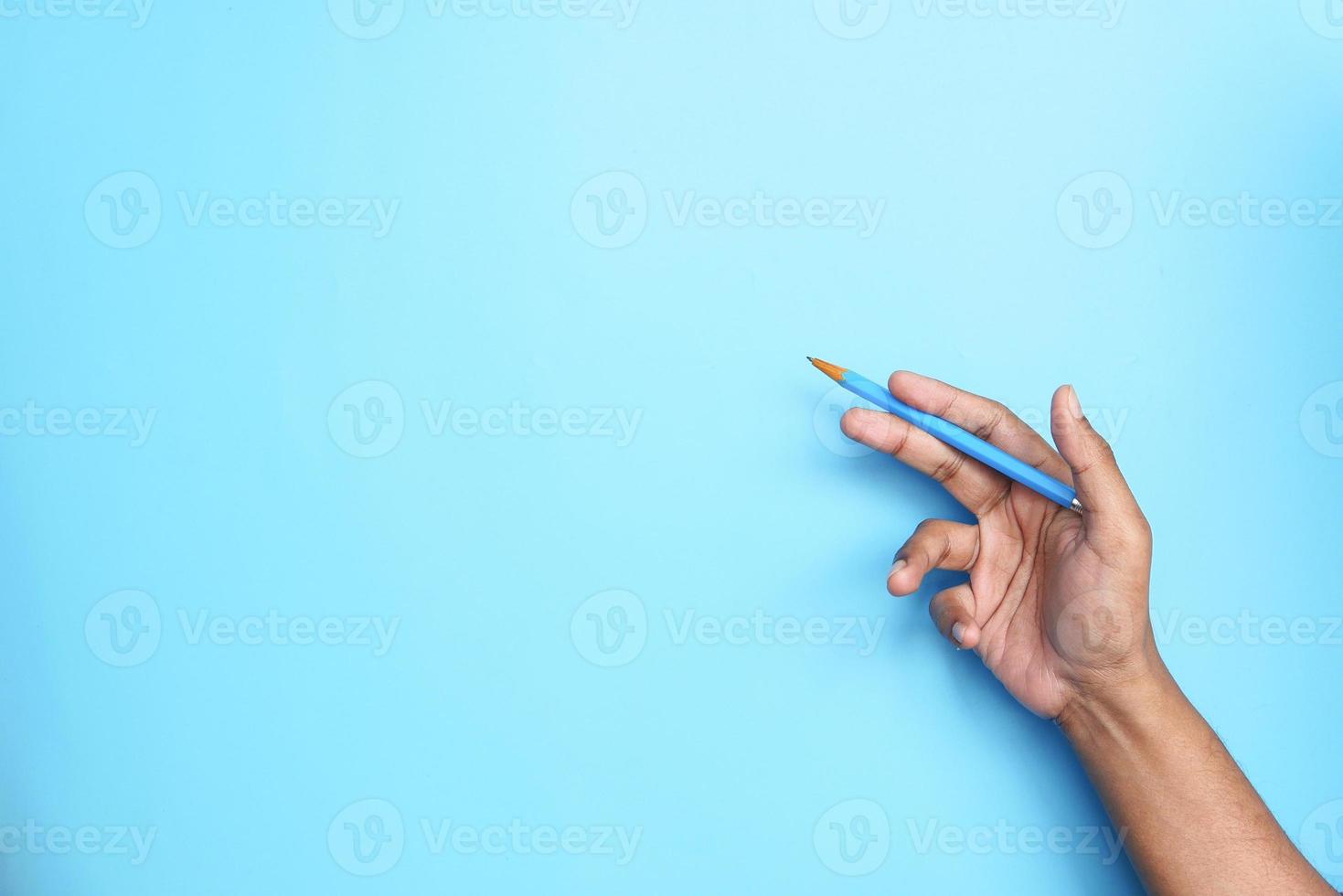 blauwe achtergrond met het potlood van de handholding en exemplaarruimte foto