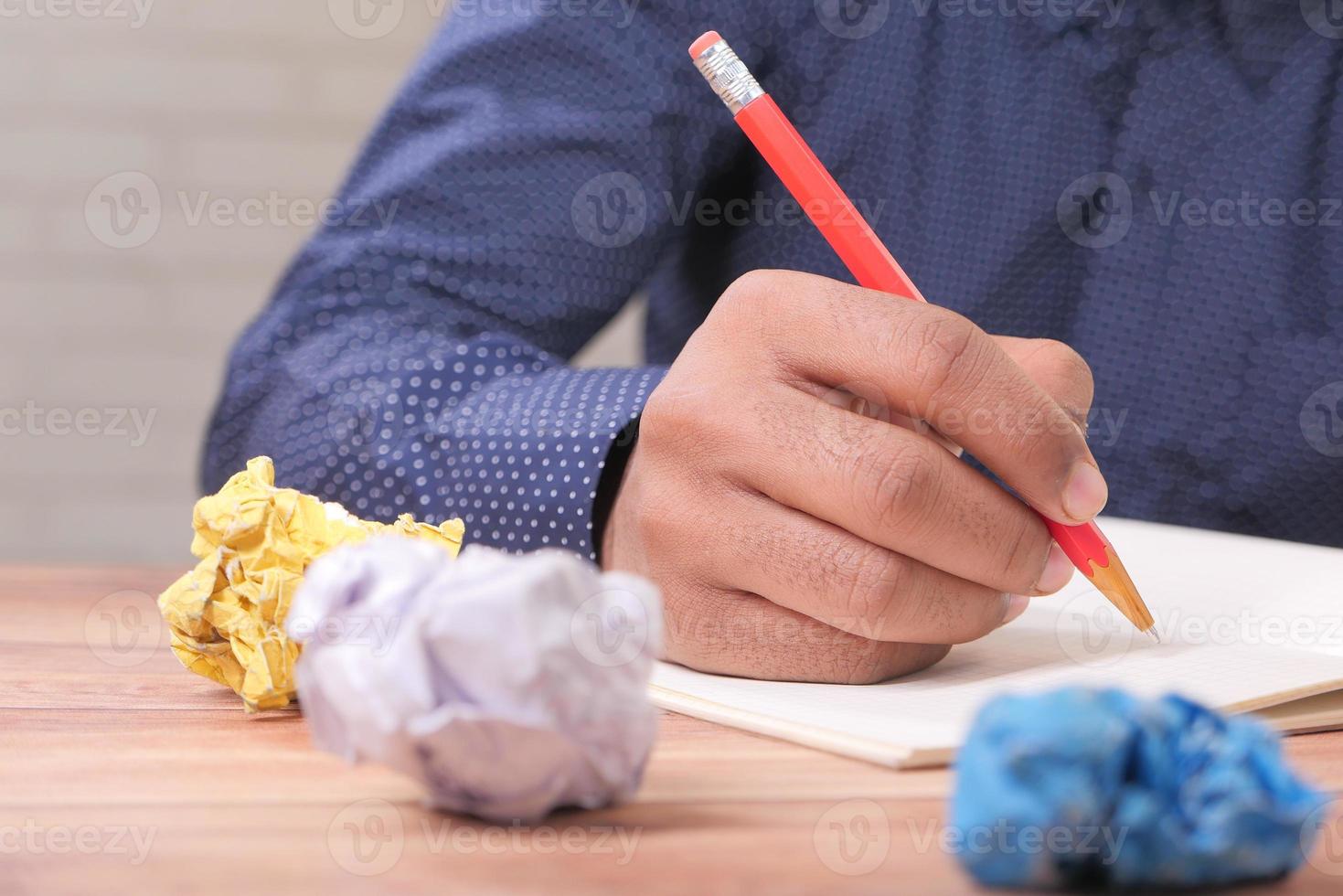 verkruimelde papieren op een bureau met een man aan het schrijven foto