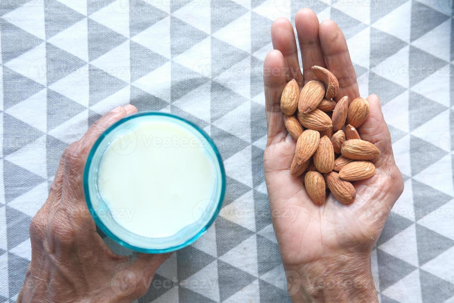 hand met amandelen en een glas melk foto