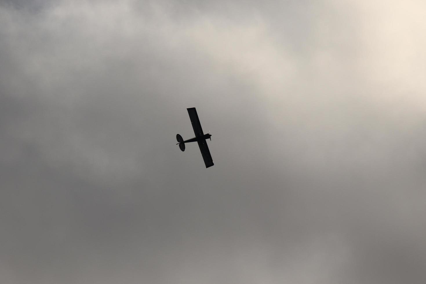 klein vlak vliegend in de lucht tegen donker wolken foto