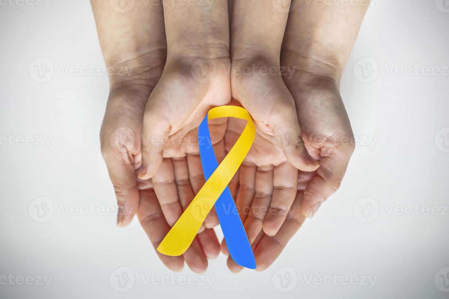 volwassen en kind handen Holding blauw en geel lint vormig papier, naar beneden syndroom bewustzijn , wereld naar beneden syndroom dag foto