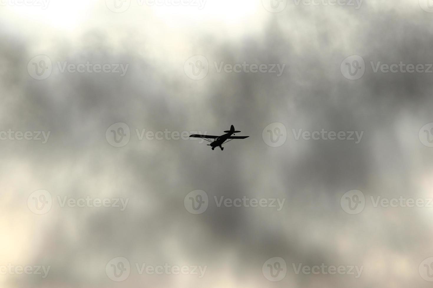 klein vlak vliegend in de lucht tegen donker wolken foto