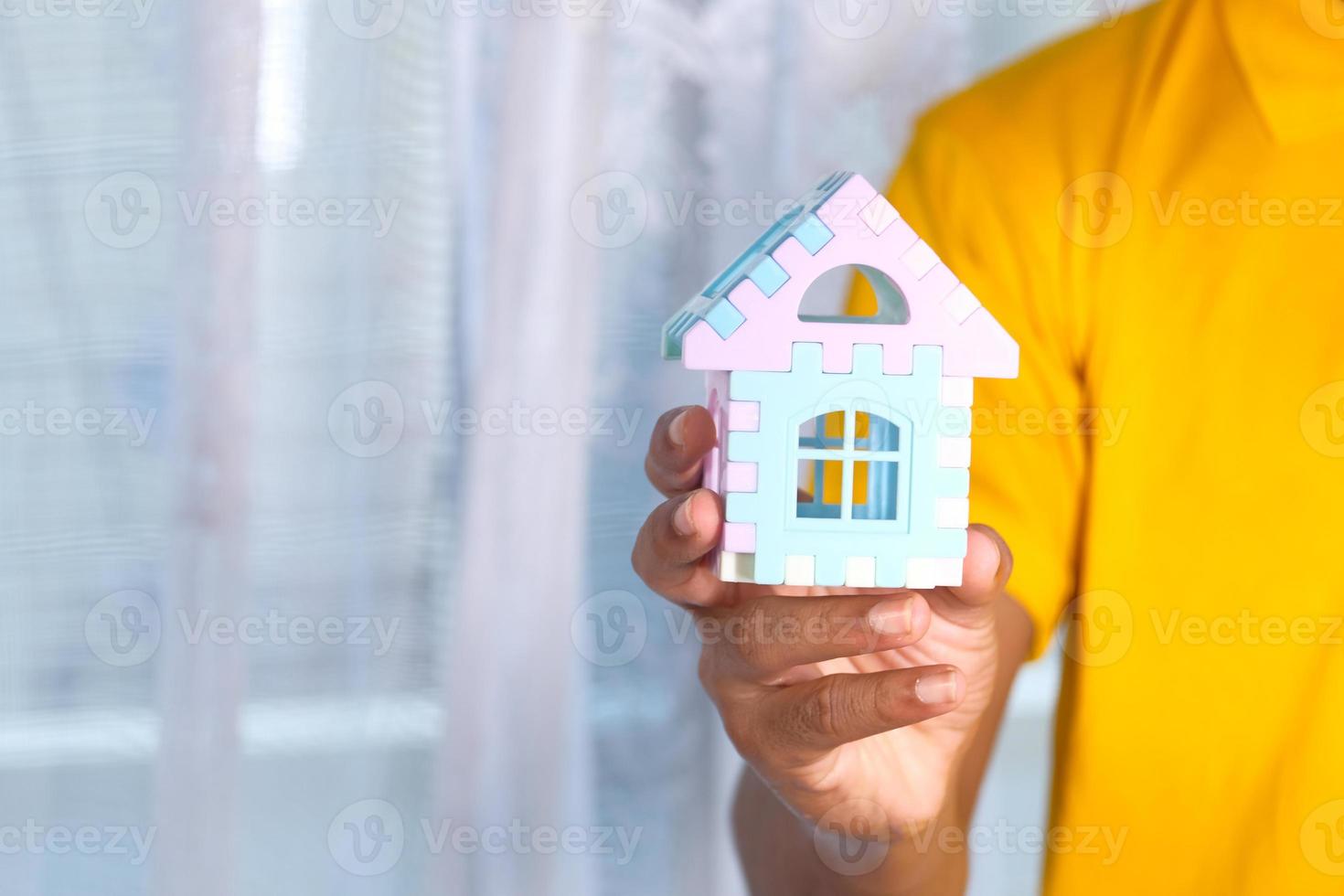 man met klein speelgoed huis foto