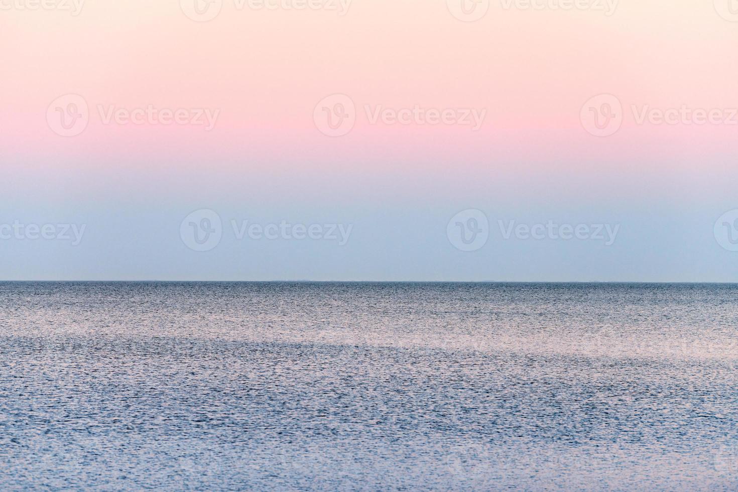 sfeervol romantisch roze rood zee zonsondergang lucht bovenstaand blauw stil water, minimalistisch vredig zeegezicht foto