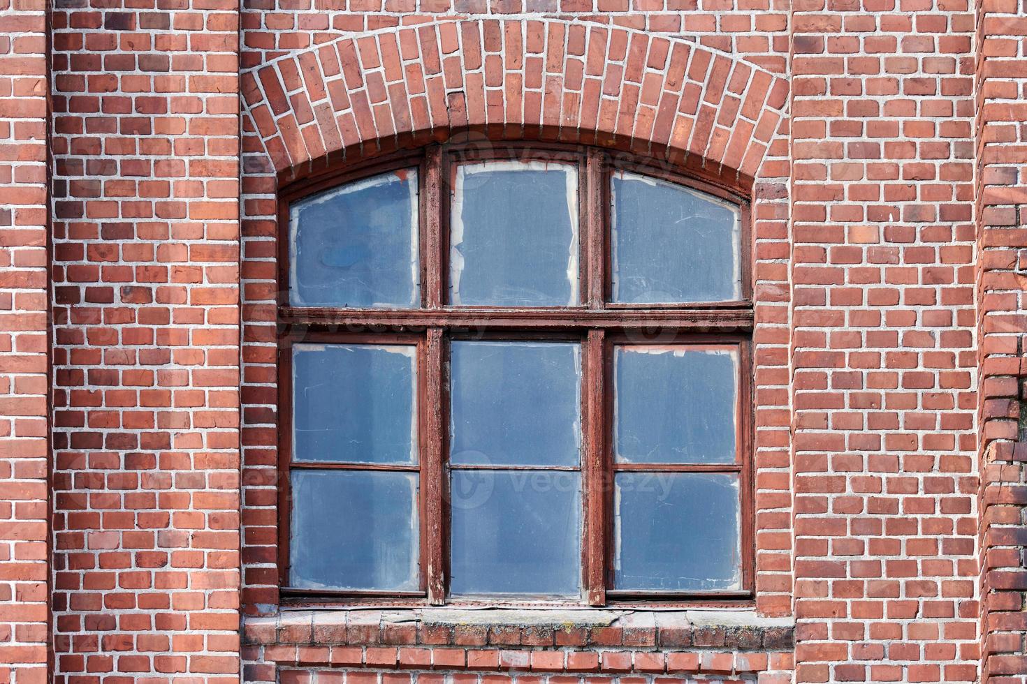 een gebogen glazen raam op oude rode bakstenen muur foto