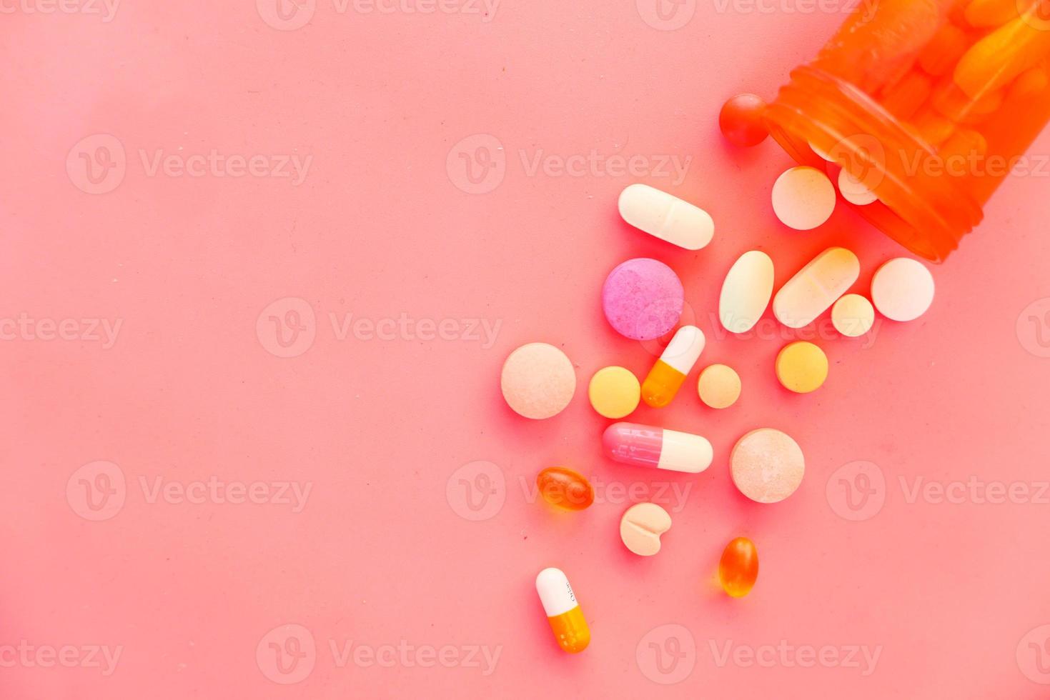 kleurrijke pillen die op roze achtergrond morsen foto