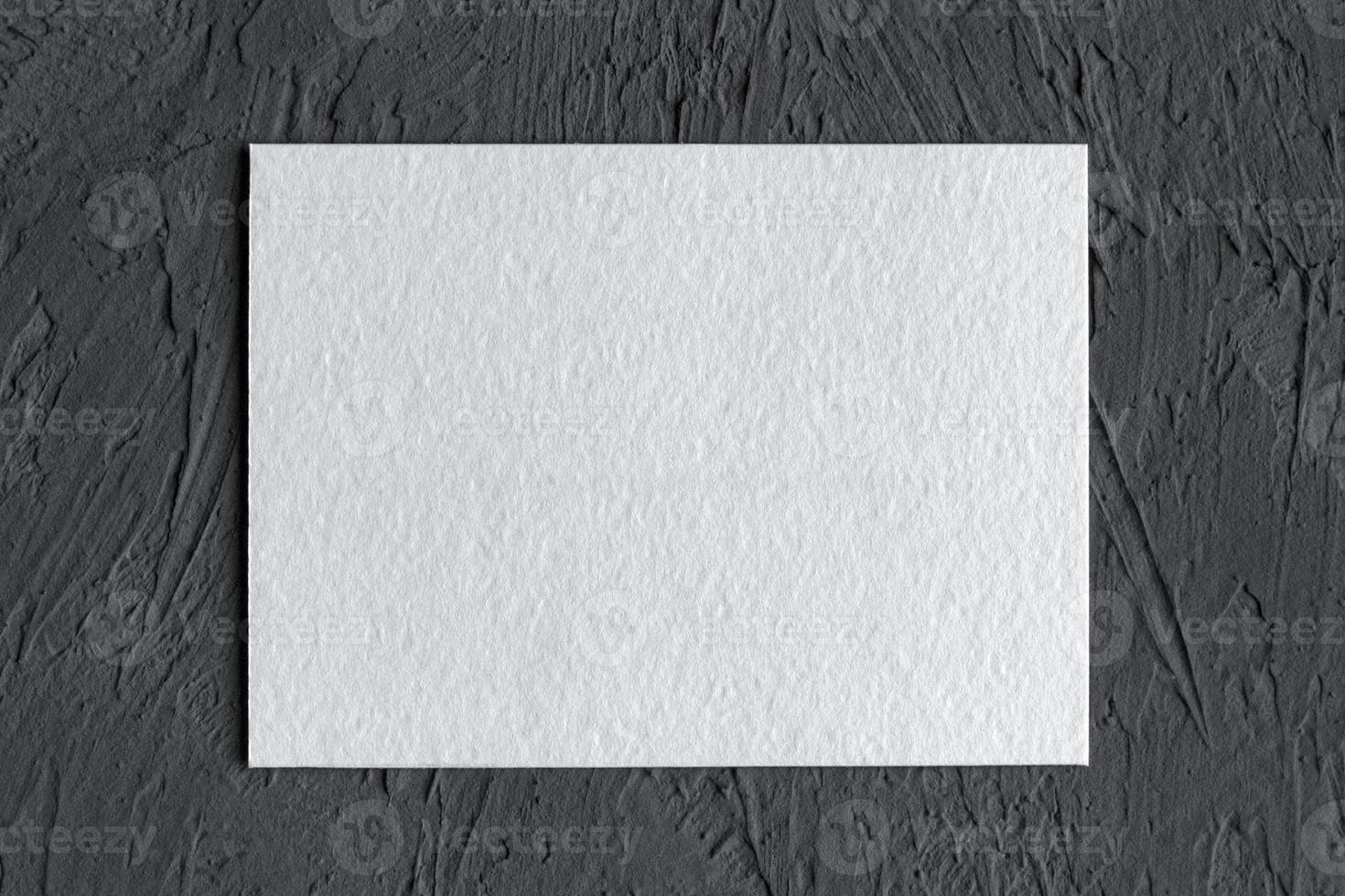 wit getextureerde papier kaart Aan donker beton achtergrond foto