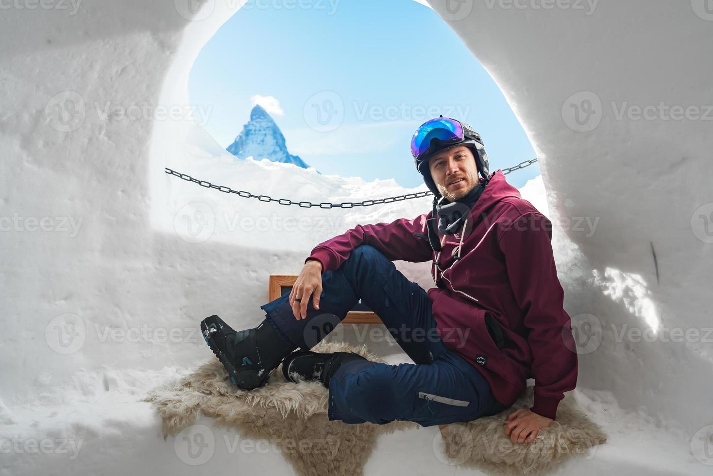 portret van glimlachen toerist snowboarder zittend binnen een iglu dorf met een visie Aan de beroemd besneeuwd matterhorn berg. ontspannende in Zwitsers Alpen, zermatt ski toevlucht. foto