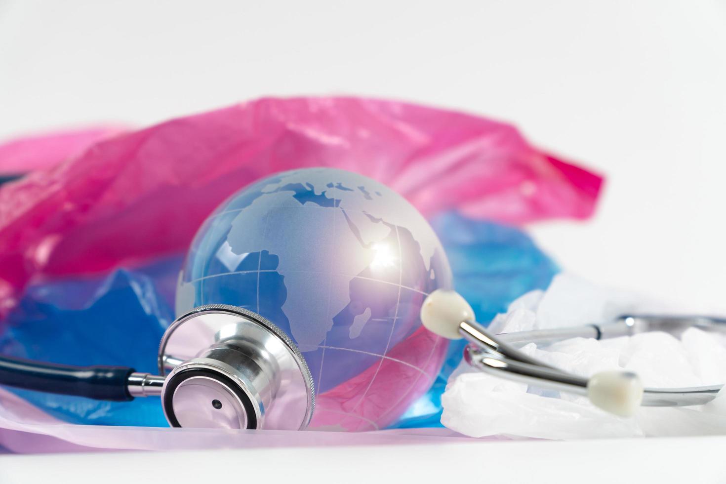 kristallen bol en stethoscoop op plastic zak. plastic afval stroomt over de wereld, de wereld is ziek, opwarming van de aarde en klimaatverandering. foto