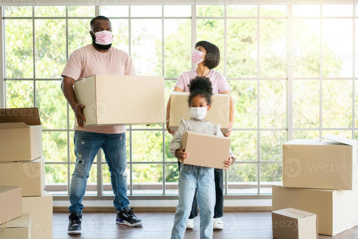 gezinnen van gemengd ras dragen kartonnen dozen en lopen op verhuisdag van de voordeur het huis in een nieuw huis in. concept van verhuizing, verhuur en huiseigenaar die naar huis verhuist. foto