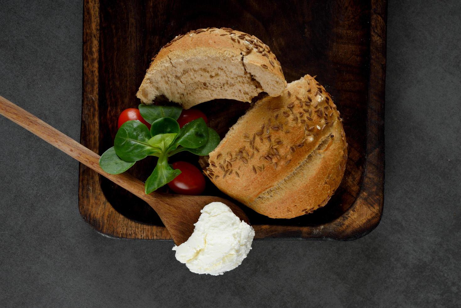 ontbijtroomkaas, tomaten en graanbagels op een grijze ondergrond foto