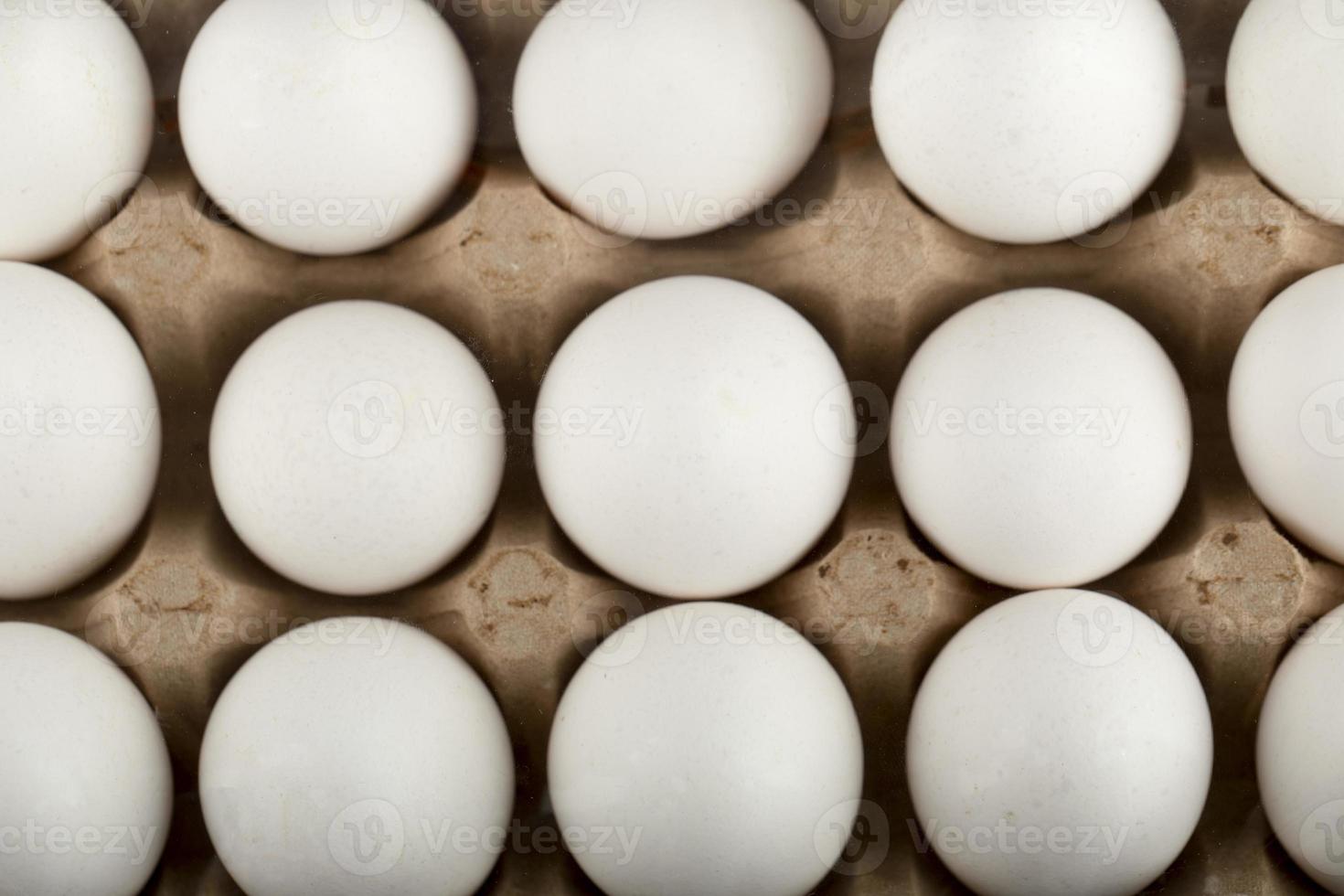 rauwe kippeneieren in een eierdoos op een marmeren achtergrond foto