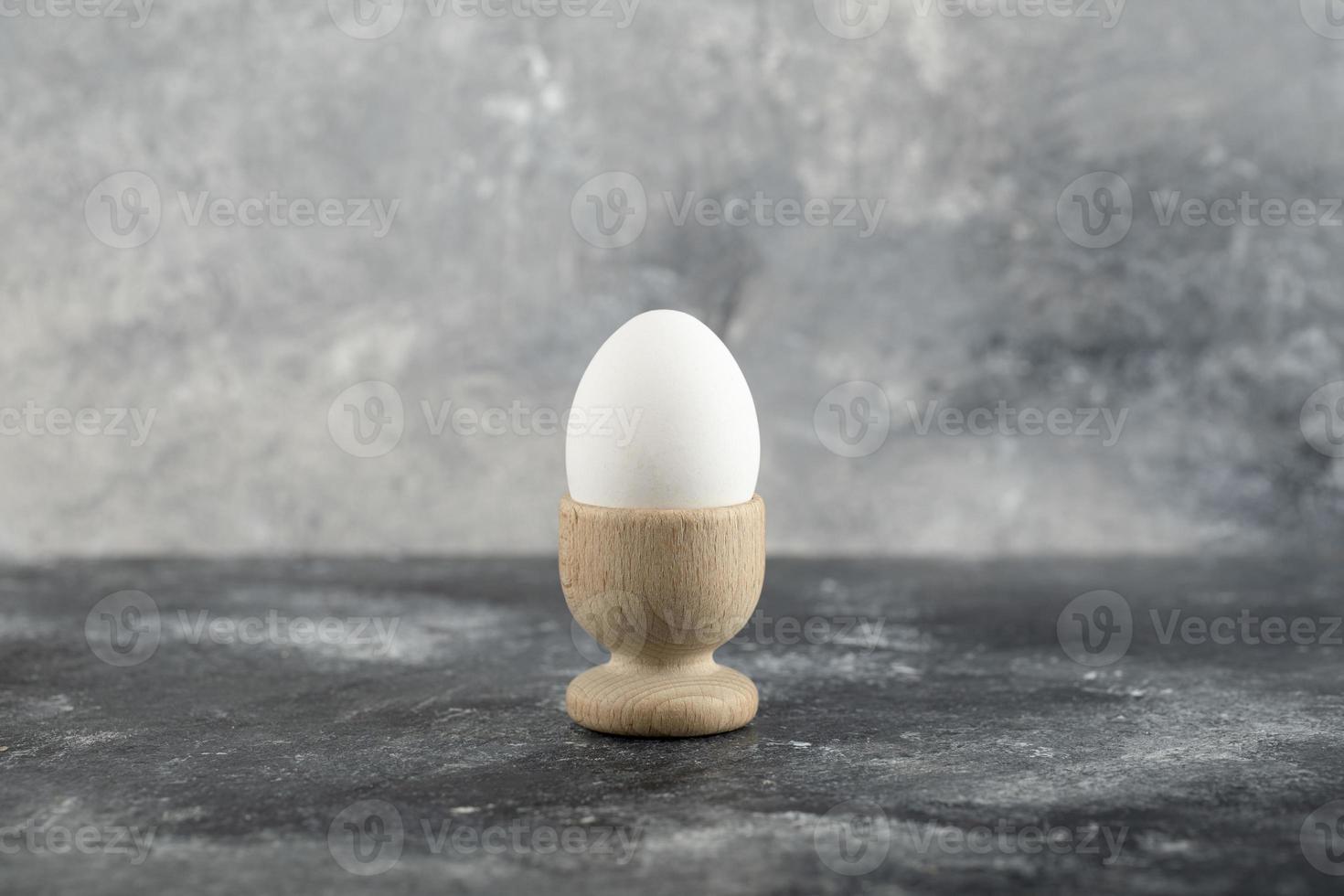 een houten eierdopje met een gekookt kippenei foto